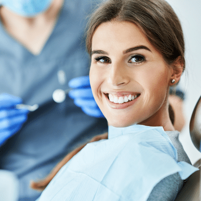 Woman smiling and sitting in a dentist chair, representing how botox® can treat dental problems