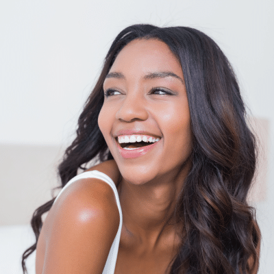 Woman smiling and looking away, representing the psychological benefits of a beautiful smile