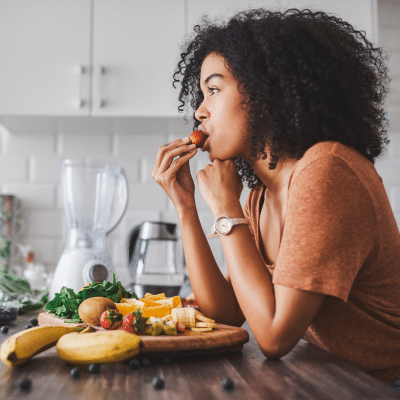 A woman eating a strawberry, representing what to eat for healthy teeth
