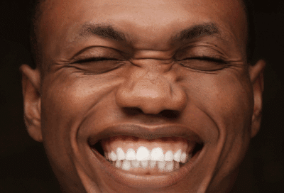 A man smiling with his eyes closed, showing his teeth, representing fun facts about teeth