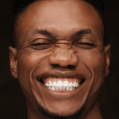 A man smiling with his eyes closed, showing his teeth, representing fun facts about teeth