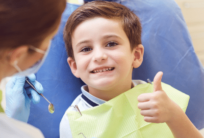 Child at dentist giving thumbs up, representing come up with seo title and description for wordpress image using the information below while keeping keyword intact