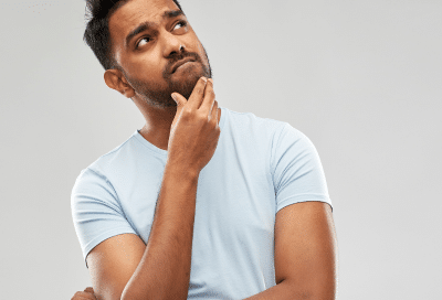 Thoughtful person in light blue shirt, representing common dental myths and misconceptions
