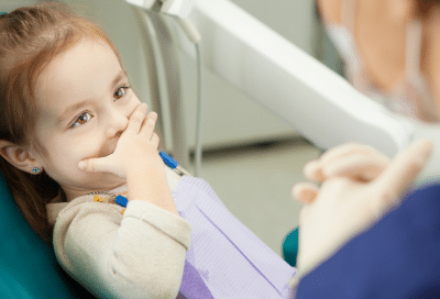 Child at dentist, nervous but smiling, representing how to overcome the fear of dentists