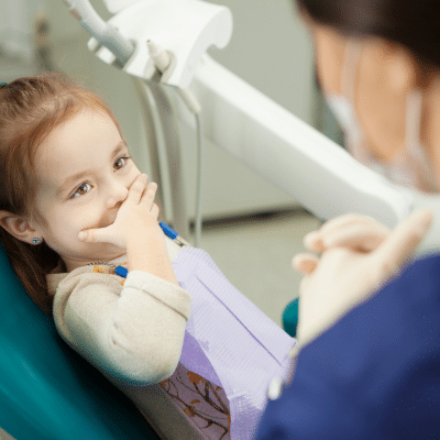 Child at dentist, nervous but smiling, representing how to overcome the fear of dentists