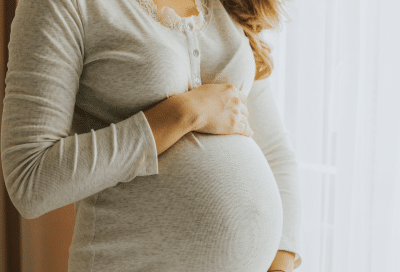 Expectant mother holding her stomach, representing dental care for expecting mothers