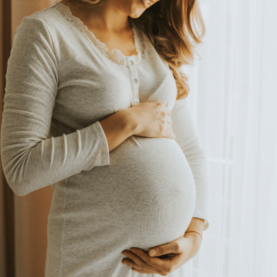 Expectant mother holding her stomach, representing dental care for expecting mothers